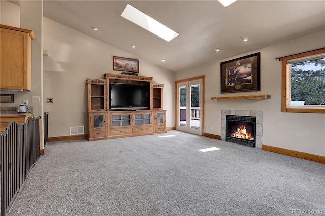 unfurnished living room with a tile fireplace, carpet, and lofted ceiling with skylight