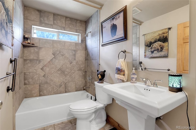 bathroom with tiled shower / bath combo, tile patterned floors, and toilet