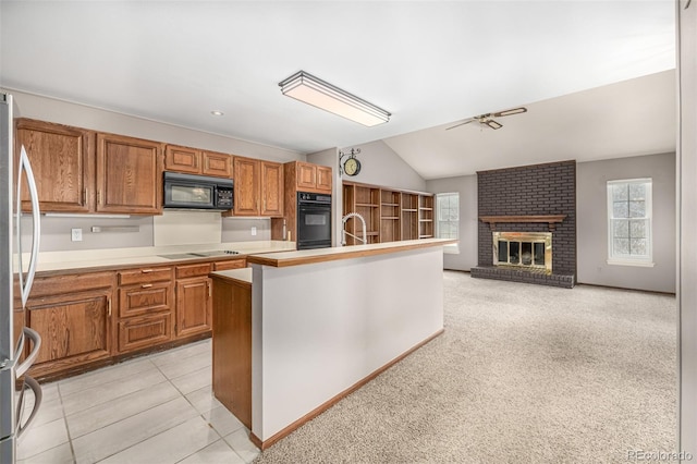 kitchen featuring light countertops, lofted ceiling, brown cabinets, a fireplace, and black appliances