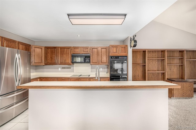 kitchen with a kitchen island with sink, a sink, black appliances, light countertops, and brown cabinets