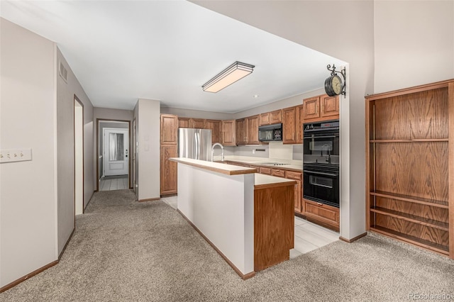 kitchen featuring light carpet, black appliances, light countertops, and a kitchen island with sink