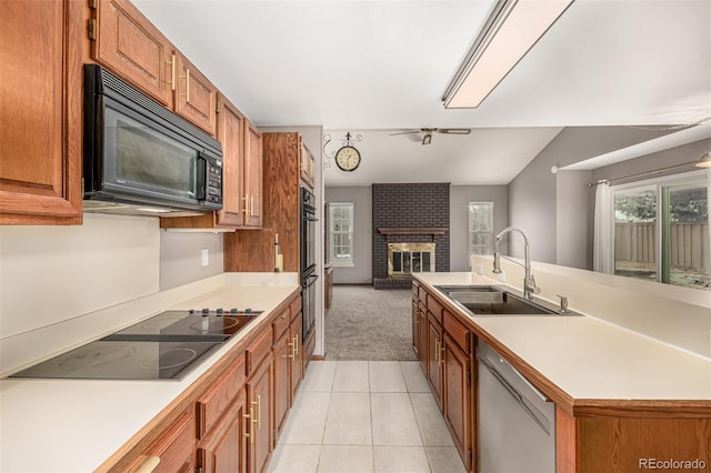 kitchen with black appliances, a sink, open floor plan, a fireplace, and light countertops