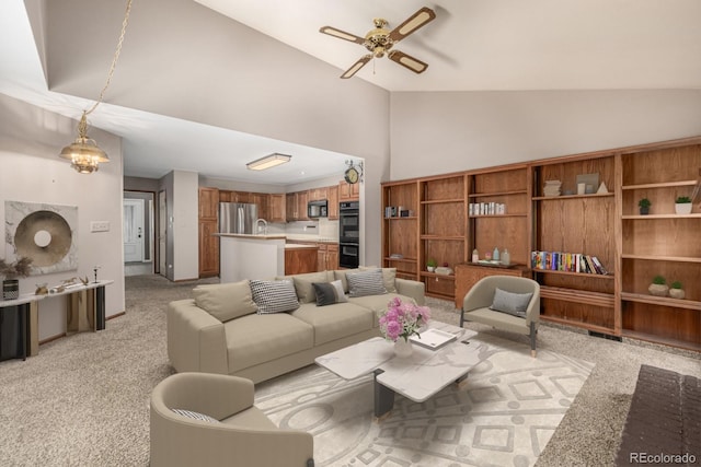 living area featuring high vaulted ceiling, ceiling fan with notable chandelier, and light carpet