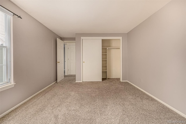 unfurnished bedroom with a closet, multiple windows, baseboards, and carpet