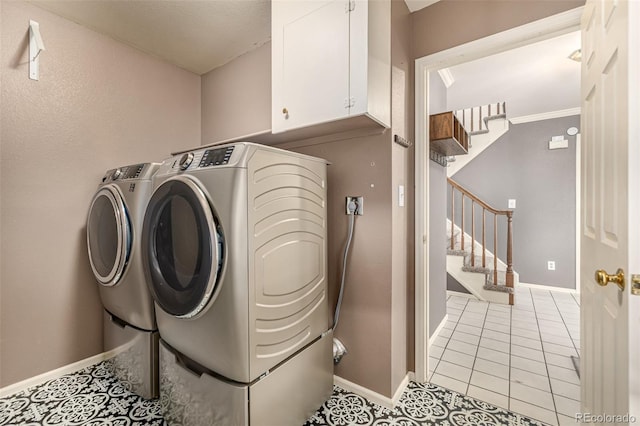 clothes washing area with washer and dryer, baseboards, cabinet space, and light tile patterned floors