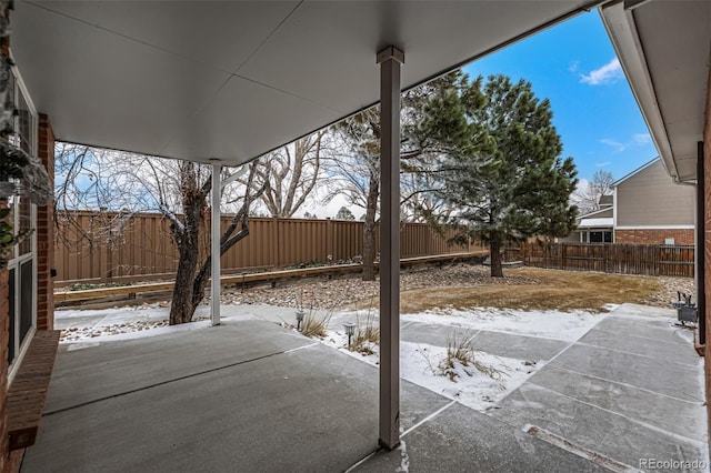 snow covered patio with a fenced backyard