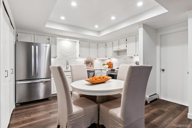 dining room featuring dark hardwood / wood-style floors, a baseboard heating unit, and a tray ceiling