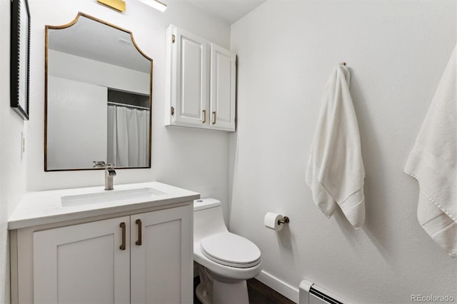 bathroom featuring a baseboard heating unit, vanity, and toilet