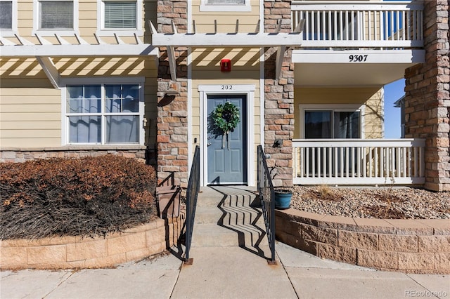 entrance to property featuring a balcony and stone siding