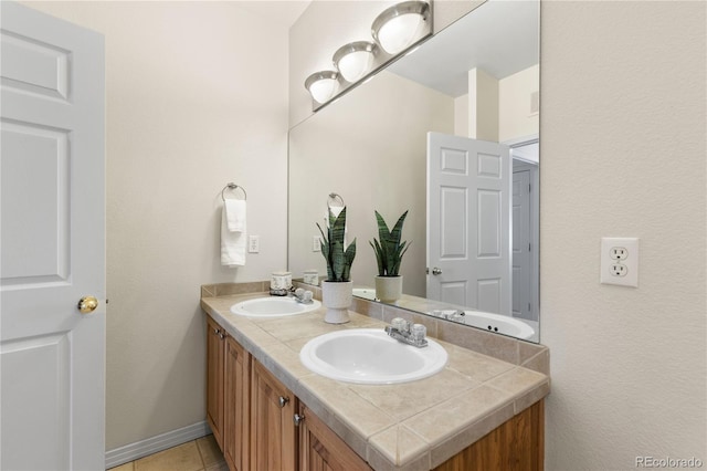 bathroom with double vanity, baseboards, a sink, and tile patterned floors