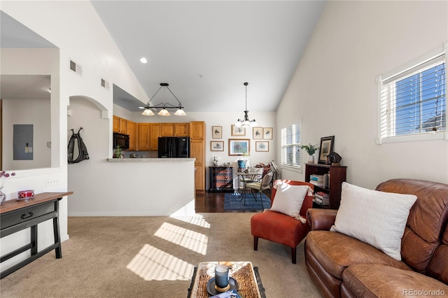 living room featuring high vaulted ceiling, light colored carpet, visible vents, electric panel, and an inviting chandelier