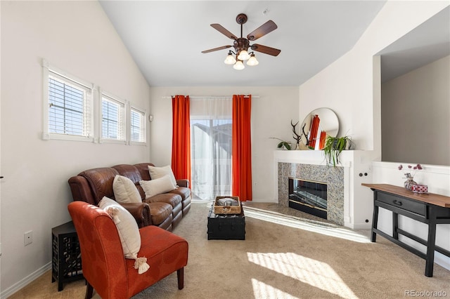 carpeted living area with a fireplace, vaulted ceiling, baseboards, and ceiling fan