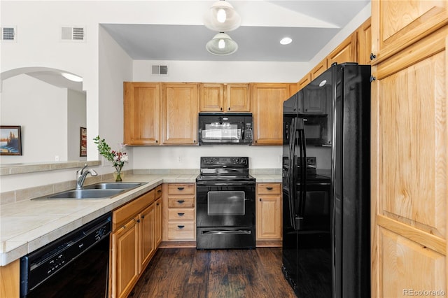 kitchen with tile counters, visible vents, a sink, and black appliances