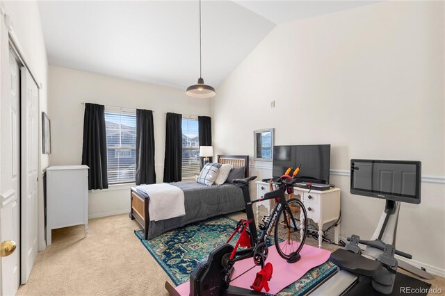 bedroom featuring high vaulted ceiling, a closet, light carpet, and baseboards