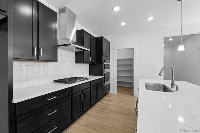 6129 Zebulon Pl, Timnath, CO 80547 - kitchen with a sink, appliances with stainless steel finishes, wall chimney exhaust hood, dark cabinetry, and light wood-style floors