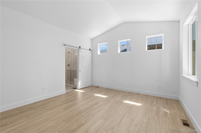 6129 Zebulon Pl, Timnath, CO 80547 - empty room with a barn door, vaulted ceiling, light wood-style flooring, and baseboards