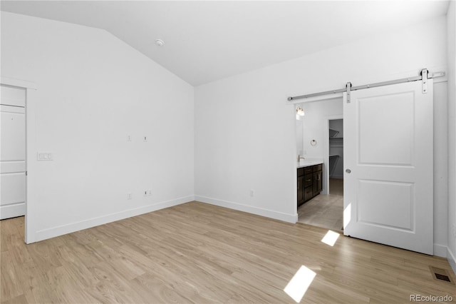 6129 Zebulon Pl, Timnath, CO 80547 - spare room featuring a barn door, lofted ceiling, light wood-style floors, and baseboards