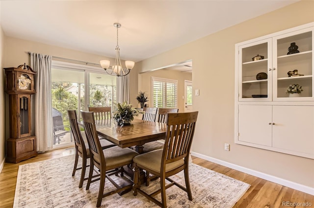 dining room with light wood-type flooring, a chandelier, and baseboards