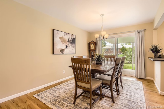dining room with a chandelier, light wood-style flooring, and baseboards
