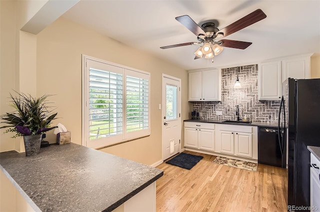 kitchen featuring dark countertops, black appliances, a sink, and white cabinets