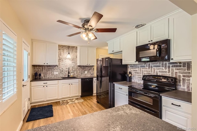 kitchen with black appliances, a sink, dark countertops, ceiling fan, and light wood-style floors
