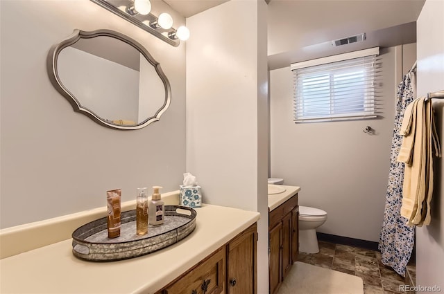 bathroom with vanity, toilet, stone finish flooring, and baseboards