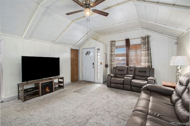 carpeted living room with ceiling fan, vaulted ceiling, and wooden walls