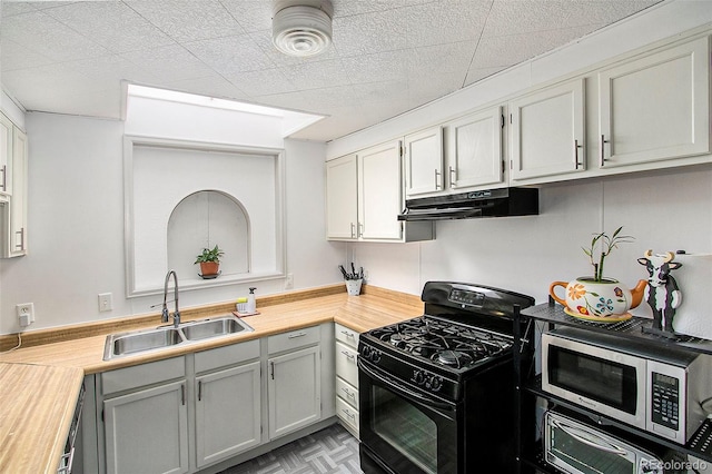 kitchen with sink, light parquet floors, black range with gas cooktop, and wooden counters