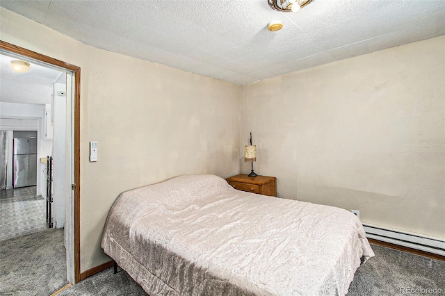 bedroom with baseboard heating, carpet flooring, and stainless steel fridge