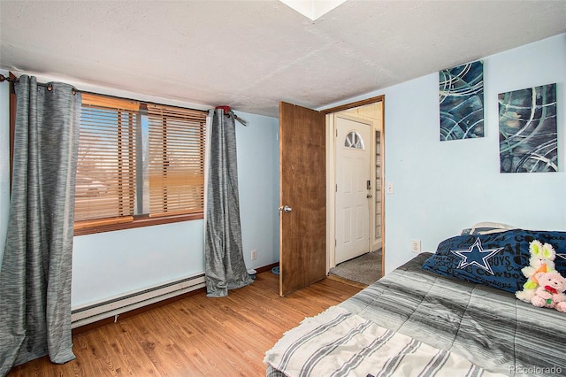 bedroom featuring a textured ceiling, wood-type flooring, and a baseboard radiator