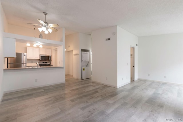 4283 S Salida Way Unit 12, Aurora, CO 80013 - unfurnished living room featuring ceiling fan, stacked washer and clothes dryer, light wood-type flooring, a textured ceiling, and high vaulted ceiling