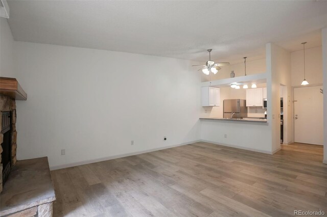 4283 S Salida Way Unit 12, Aurora, CO 80013 - unfurnished living room featuring a fireplace with raised hearth, ceiling fan, and light wood finished floors