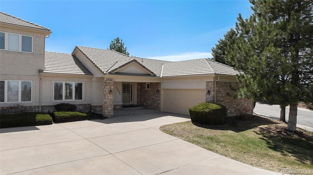 13806 E Chenango Dr, Aurora, CO 80015 - view of front of home with a tile roof, driveway, stone siding, an attached garage, and stucco siding
