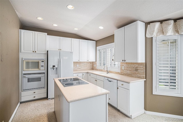 13806 E Chenango Dr, Aurora, CO 80015 - kitchen featuring white appliances, baseboards, a sink, a center island, and lofted ceiling