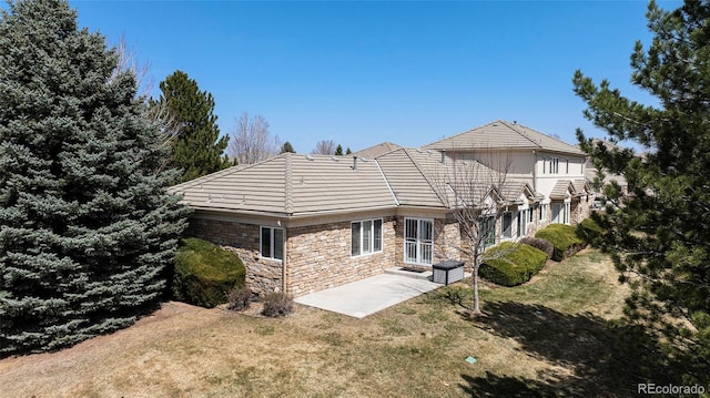 13806 E Chenango Dr, Aurora, CO 80015 - back of house featuring a patio area, stone siding, a lawn, and a tiled roof