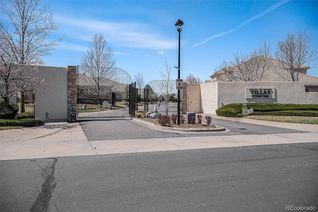 13806 E Chenango Dr, Aurora, CO 80015 - view of asphalt street with a gate, curbs, and a gated entry