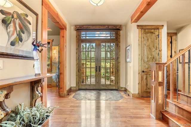 foyer featuring french doors, light wood-type flooring, and beamed ceiling