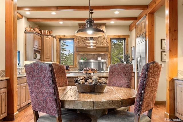 dining area with beam ceiling and light hardwood / wood-style flooring