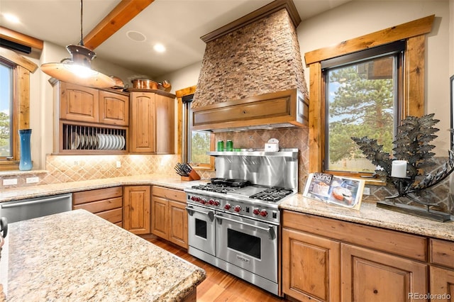 kitchen with stainless steel appliances, light stone countertops, backsplash, and a healthy amount of sunlight