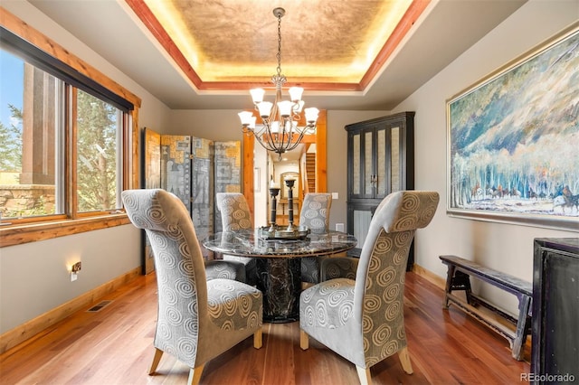 dining area featuring hardwood / wood-style flooring, a chandelier, and a tray ceiling