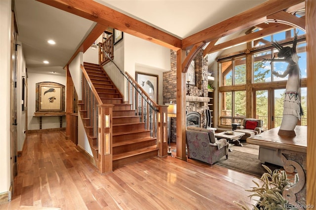 interior space featuring a high ceiling, french doors, a fireplace, hardwood / wood-style flooring, and beam ceiling