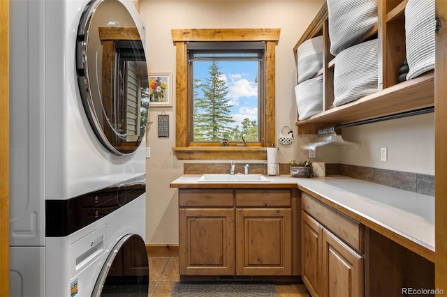 interior space with sink, cabinets, stacked washer / dryer, and dark tile patterned floors