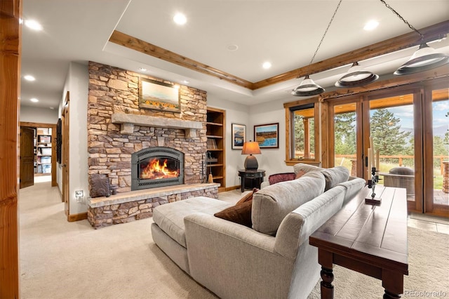 living room with light colored carpet, a tray ceiling, and a stone fireplace