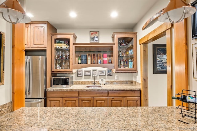 kitchen with light stone countertops, appliances with stainless steel finishes, and sink