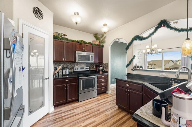 kitchen featuring sink, light hardwood / wood-style floors, a chandelier, decorative light fixtures, and appliances with stainless steel finishes