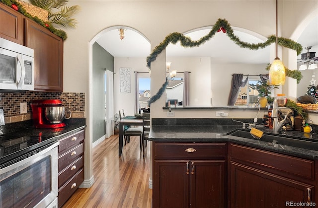 kitchen featuring sink, hanging light fixtures, light hardwood / wood-style flooring, tasteful backsplash, and range