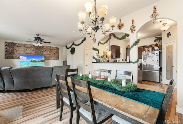 dining area featuring light wood-type flooring and ceiling fan with notable chandelier