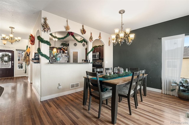 dining room featuring hardwood / wood-style flooring, a healthy amount of sunlight, and an inviting chandelier