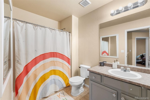 bathroom with vanity, curtained shower, toilet, and a textured ceiling