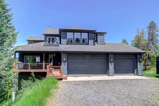 30889 Manitoba Dr, Evergreen, CO 80439 - view of front facade featuring driveway, a shingled roof, a porch, and an attached garage